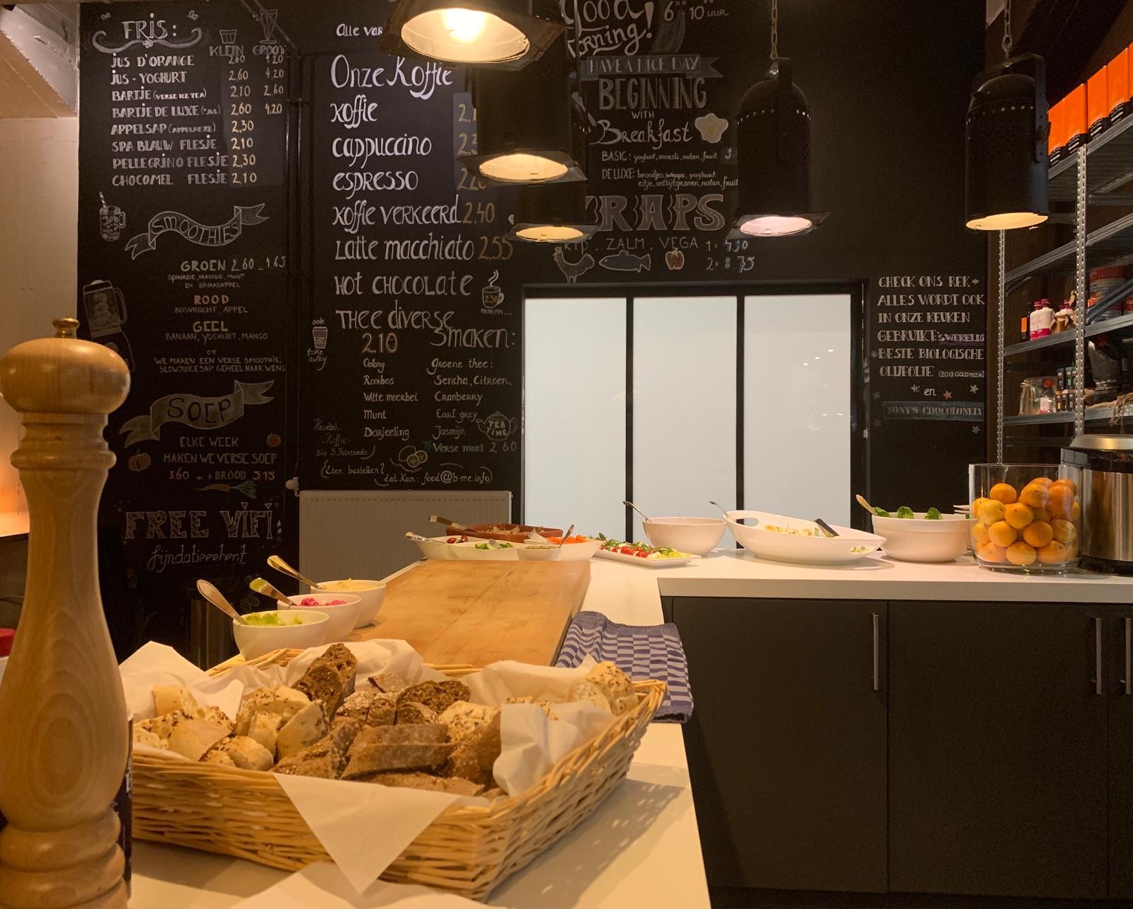 Manden met dagvers brood bij de toonbank van B-Food, met het krijtbordmenu