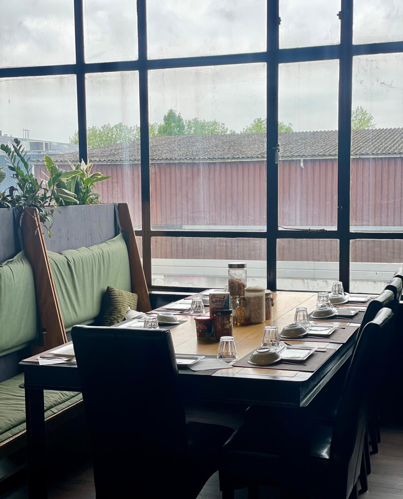 Een gedekte tafel bij de hoge fabrieksramen van B-me